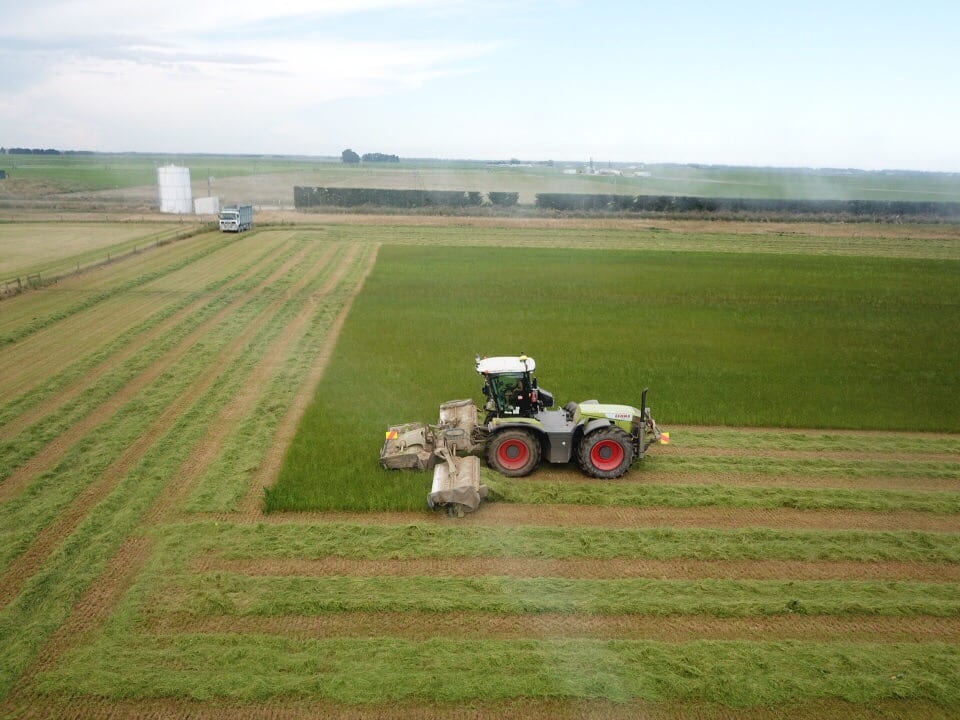 Agricultural machinery working in a paddock on a cloudy day